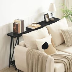 a living room with white couches and pillows on top of the sofa, next to a black coffee table