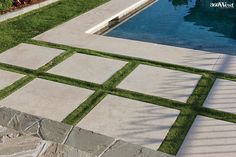 the grass is growing on the stone walkway by the pool in the back yard,