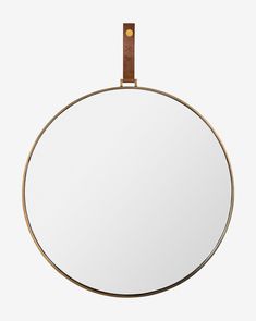 a round mirror with a leather strap hanging from it's side, against a white background