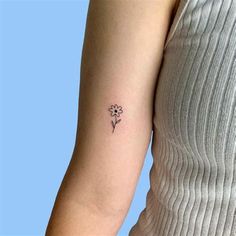 a woman's arm with a small flower tattoo on the left side of her arm