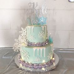 a three tiered cake decorated with snowflakes and icing