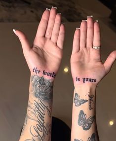 two hands with tattoos that say the world is yours and butterflies on their wrists