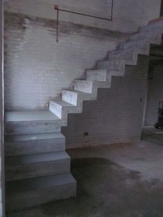 an empty room with white brick walls and concrete steps leading up to the second floor