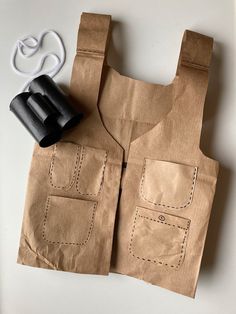 a brown paper bag with two black handles and some scissors on the table next to it