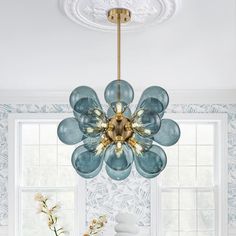 a chandelier hanging from the ceiling over a dining room table with flowers on it