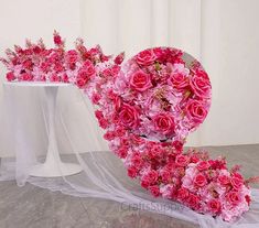 a bouquet of pink roses on a table with a veil and flowers in the background