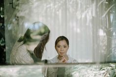 a woman standing in front of a mirror with her hand on her chin looking at herself