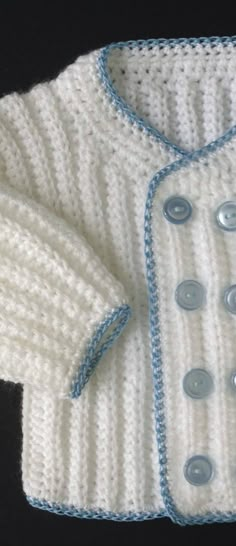 a white knitted sweater with blue trim and buttons