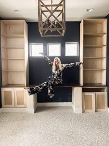 a woman is jumping in the air with her arms spread out and legs crossed on a bookcase