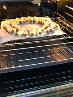 hotdogs are being cooked in an oven with buns on the rack and wrapped in paper