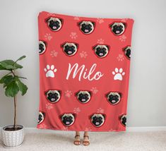 a woman standing in front of a red blanket with pugs and paw prints on it