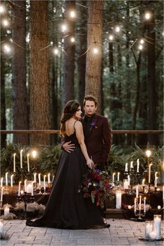 a bride and groom standing in front of candles at their outdoor wedding ceremony with lights strung from the trees