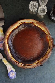 a chocolate pie sitting on top of a table next to a knife and some glasses