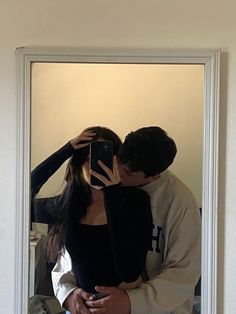 a man and woman taking a selfie in front of a mirror with their arms around each other