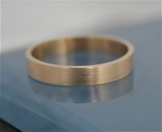 a gold wedding ring sitting on top of a blue surface