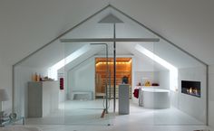 an attic bathroom with glass walls and white tile flooring, along with a free standing bathtub