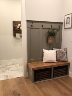 a wooden bench sitting in the middle of a room next to a wall with hooks on it