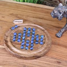 a wooden board game with blue marbles on it and a metal lion figurine