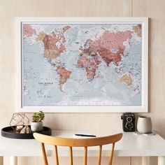 a white table with a wooden chair and a map on the wall in front of it