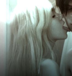 a man and woman kissing each other in front of a mirror