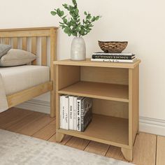 a small wooden shelf with books and a plant on it next to a bed in a bedroom