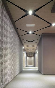 an empty hallway with white walls and black lines on the ceiling is lit by recessed lights