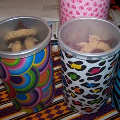 two plastic cups filled with food sitting on top of a colorful table cloth next to each other