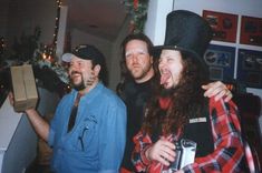 three men standing next to each other in front of a christmas tree and holding gifts