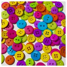 many different colored buttons on a white surface