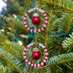 two red and white beaded ornaments hanging from a christmas tree