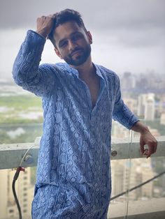 a man standing on top of a building next to a tall building with a city in the background