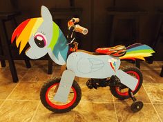 a little kid's toy bike with a rainbow pony on the front and side