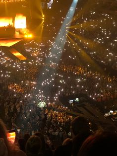 a large group of people at a concert with bright lights on the stage and in the audience