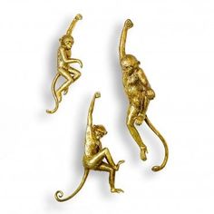 three gold monkey figurines sitting on each other's back legs and arms