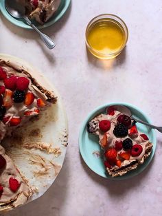 there is a piece of cake with berries on it and a bowl of honey in the background