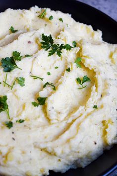 mashed potatoes with parsley on top in a black plate, ready to be eaten