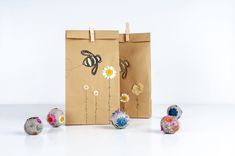 a brown paper bag with flowers and bees on it next to small balls of yarn