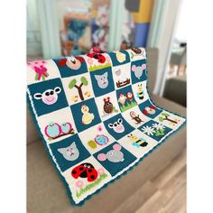 a quilted blanket with animals and ladybugs on it sitting on top of a couch