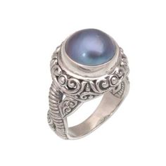 A cultured pearl tinted an iridescent blue seems to glow from the center of this magnificent cocktail ring. Bali's Putu Putri presents the ring which is crafted by hand of sterling silver. Beneath an ornately detailed crown silver bands of different patterns wind around one another. Mystical Gemstone Rings For Formal Occasions, Elegant Blue Pearl Ring With Gemstone, Elegant Iridescent Opal Ring With Cabochon, Elegant Iridescent Cabochon Opal Ring, Elegant Iridescent Cabochon Ring, Elegant Blue Pearl Ring, Elegant Blue Pearl Ring For Formal Occasions, Elegant Blue Pearl Ring As Gift, Elegant Blue Moonstone Ring For Formal Occasions