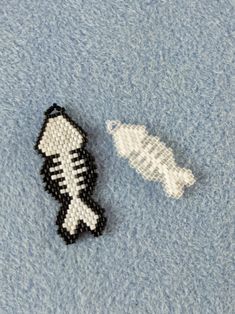 two pieces of bead art on a blue surface next to an object that looks like a fish