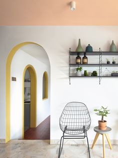 a room with a chair, potted plant and shelves on the wall