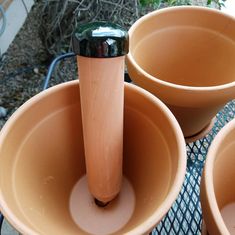 three large clay pots sitting next to each other on a metal table with a black top