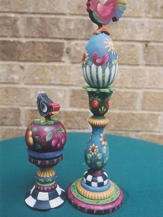 two colorful vases sitting on top of a blue table next to a brick wall