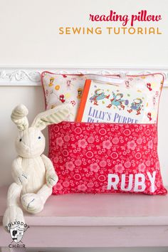 a stuffed rabbit sitting on top of a pillow next to a red and white pillow