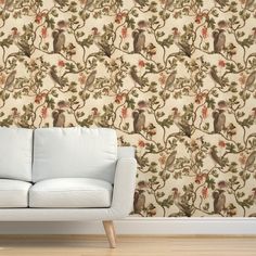 a white couch sitting in front of a wallpaper with monkeys on it's branches