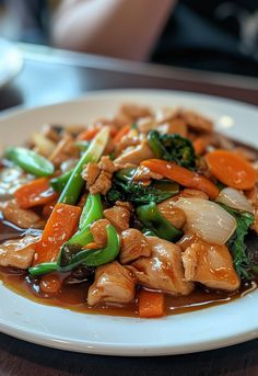 a white plate topped with chicken and veggies on top of a wooden table