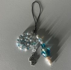 a rosary and cross hanging from a hook on a wall with light coming through it