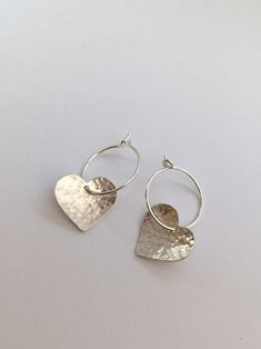 "Simple yet stylish sterling silver hoop earrings featuring a beautiful hand hammered heart. They will add a lovely touch to any outfit and will make an ideal valentines or anniversary gift. Total length: approximately 2.5 cm (0.9\") Heart: 1.5 cm (0.5\") x 1.3 cm (0.5\") Hoop size: 1.5 cm (0.5\") in diameter x 0.7mm thick. The earrings will come in a beautiful gift box." Silver Hoop Earrings With Heart Charm, Valentine's Day Small Hoop Sterling Silver Earrings, Sterling Silver Double Heart Hoop Earrings For Gifts, Silver Sterling Heart-shaped Hoop Earrings, Silver Heart-shaped Hoop Earrings In Sterling Silver, Silver Small Hoop Heart Earrings For Anniversary, Silver Sterling Silver Heart Hoop Earrings, Silver Hoop Earrings With Heart Charm For Anniversary, Silver Small Hoop Earrings With Heart Charm