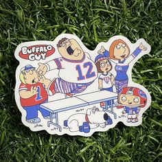 a cartoon sticker on the grass with some people around it and an image of two football