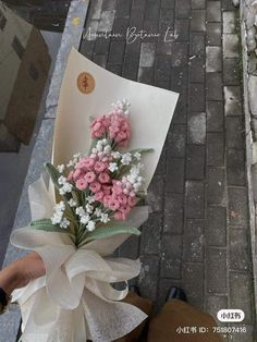 a bouquet of pink and white flowers is tied to a piece of paper on the sidewalk